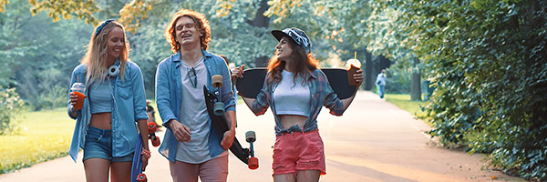 Cuenta y Libreta Joven In - Grupo de jóvenes vestidos con ropa moderna con patinetes, sonriendo junto a un parque rodeado de arboles Cuenta y Libreta Joven In - Grupo de jóvenes vestidos con ropa moderna con patinetes, sonriendo junto a un parque rodeado de arboles