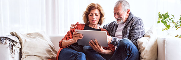 Programa Te lo Mereces Pensión - Una pareja jubilada relajada en casa utilizando una tableta digital Programa Te lo Mereces Pensión - Una pareja jubilada relajada en casa utilizando una tableta digital