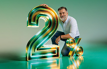 Un "2%" con textura metálica y con neones y brillos en el cual se apoya un señor con barbas blancas