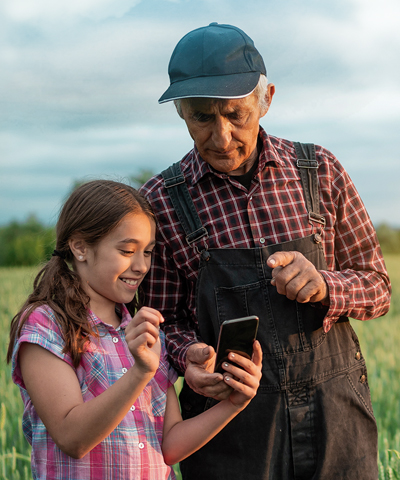 porque somos así Agro: Agricultor senior con una niña viendo el campo y un móvil