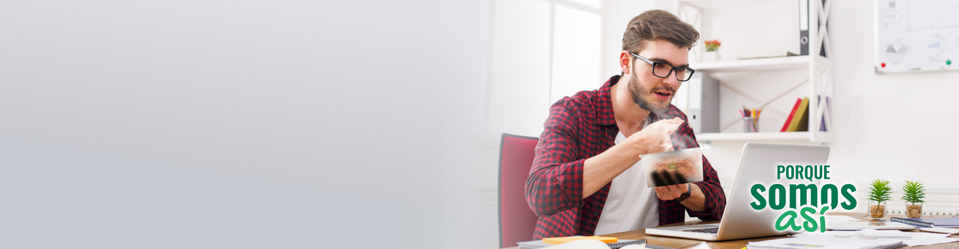 Porque somos Así nómina - chico comiendo de un taper ware, mientras trabaja con un ordenados portátil