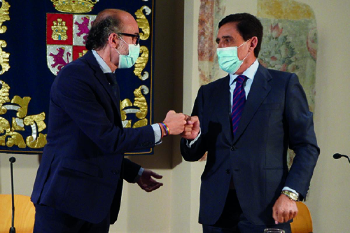Consejero de cultura y Carlos Martínez Izquierdo Presidente de de la Unión de Cajas Rurales de Castilla y León chocan el puño en señal de acuerdo de firman.