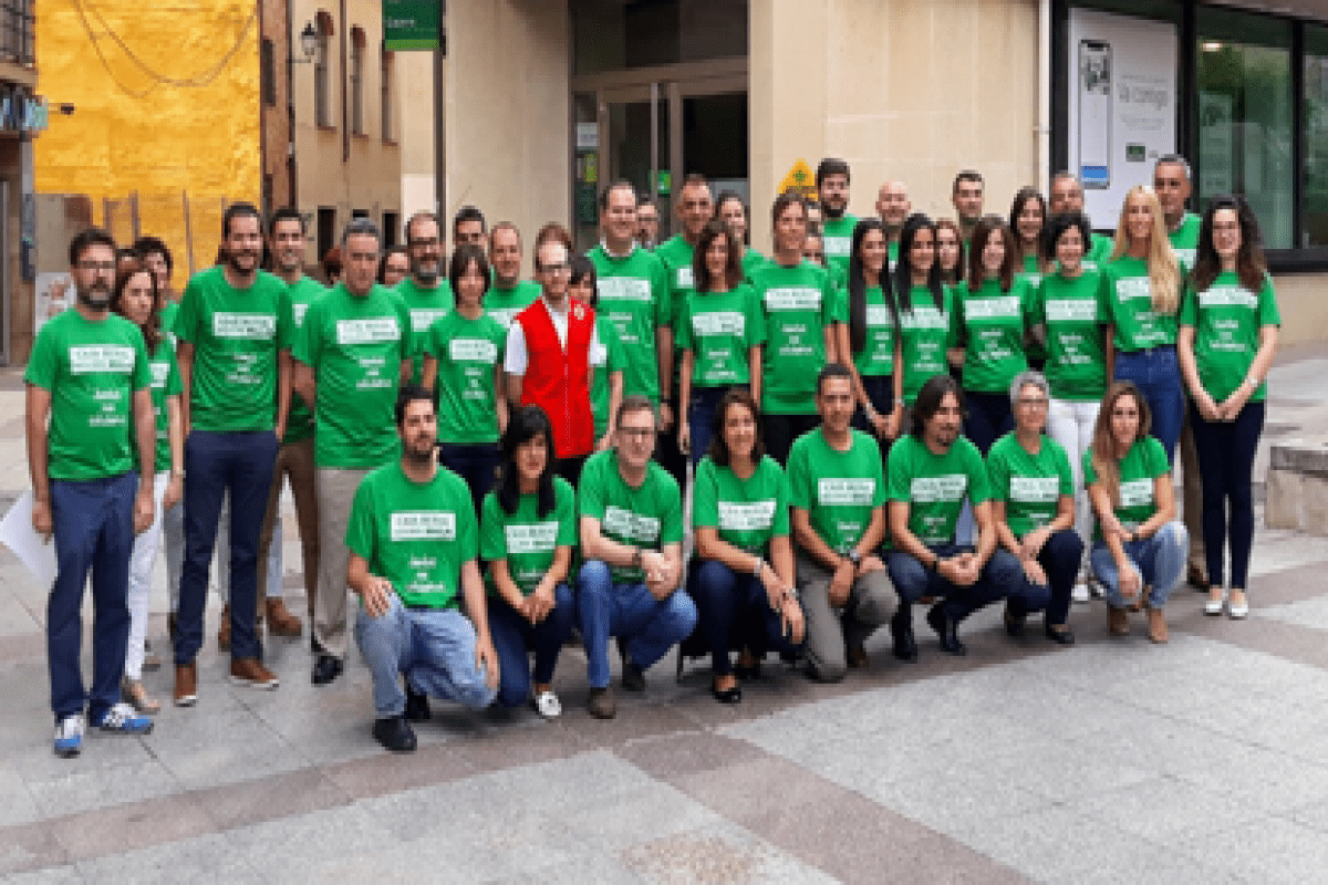 Empleados de Caja Rural de Soria lucen camisetas verdes para apoyar a una asociacion. 