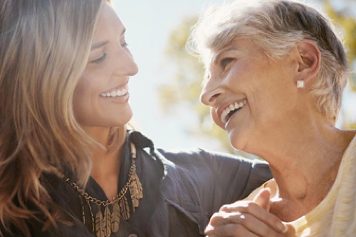 Madre e hija mirandose a los ojos, sonriendo y cogidas de la mano, vinculando la mediana edad con los planes de futuro para la jubilación. 