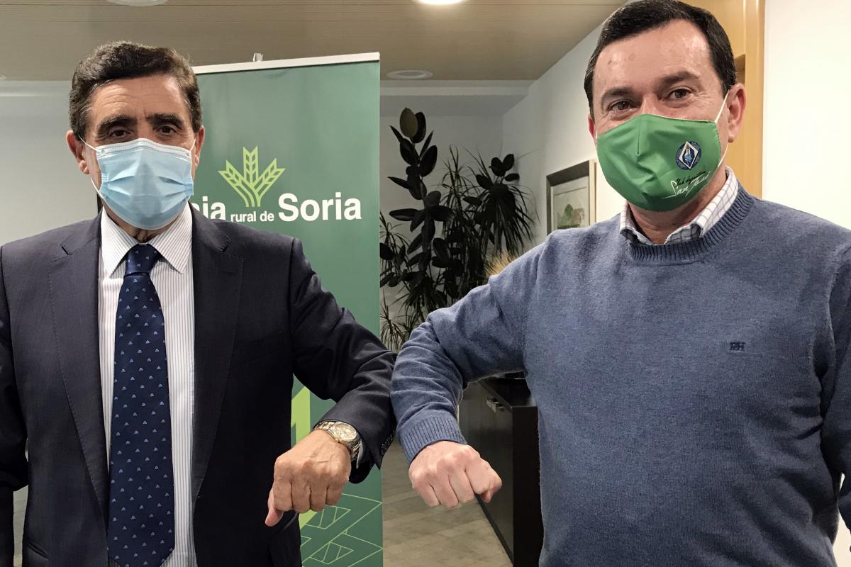 Foto Presidente Caja Rural de Soria D. Carlos Martínez y Presidente C.D. San José chocando el codo sobre fondo de anagrama de Caja Rural de Soria