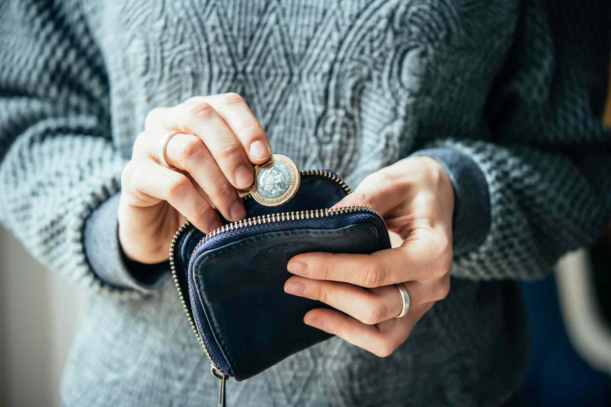 Mujer metiendo una moneda a la cartera Mujer metiendo una moneda a la cartera