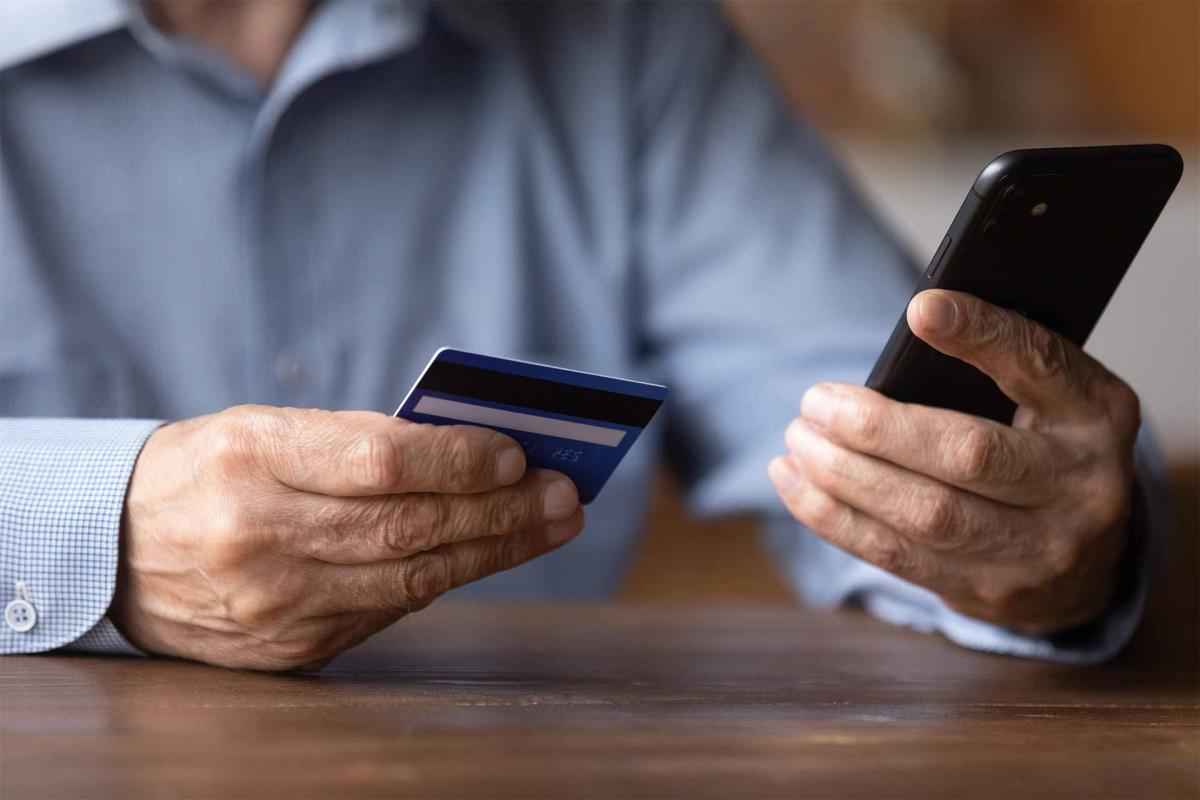 Hombre sujetando el movil y una tarjeta de crédito Hombre sujetando el movil y una tarjeta de crédito