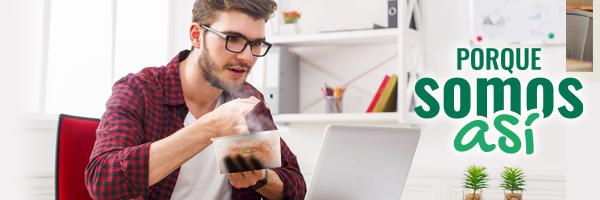 Porque somos Así nómina - chico comiendo de un taper ware, mientras trabaja con un ordenados portátil